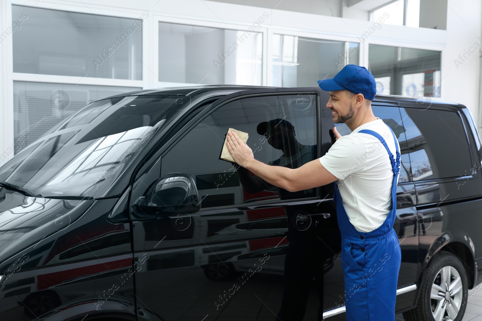 Photo of Worker tinting car window with foil in workshop