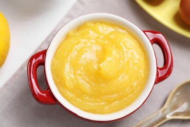 Delicious lemon curd in bowl and spoon on table, flat lay