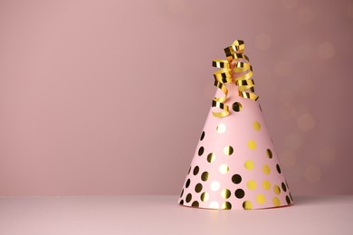 Party hat and serpentine streamers on dusty pink background, space for text