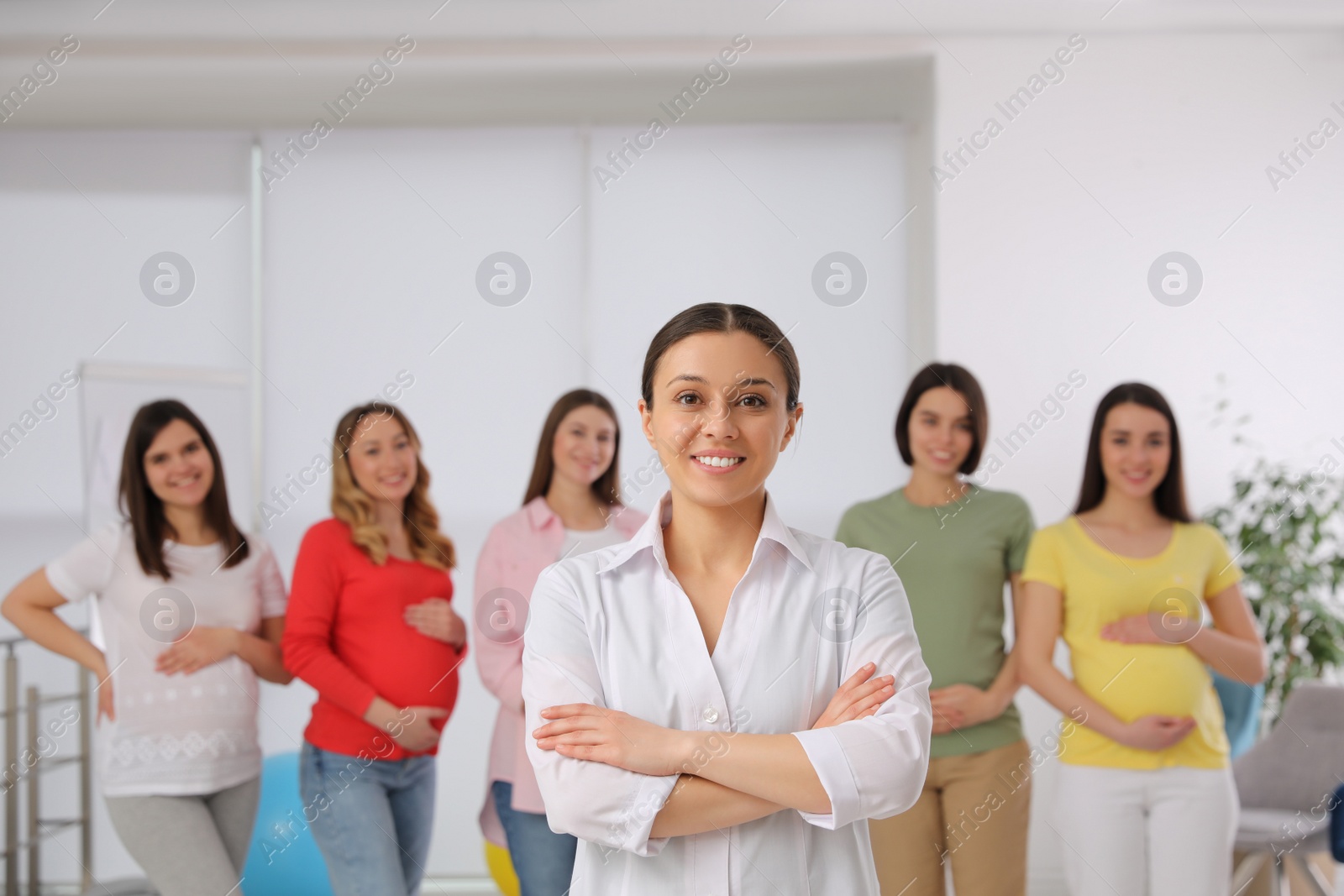 Photo of Group of pregnant women with doctor at courses for expectant mothers indoors