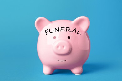 Image of Money for funeral expenses. Pink piggy bank on light blue background