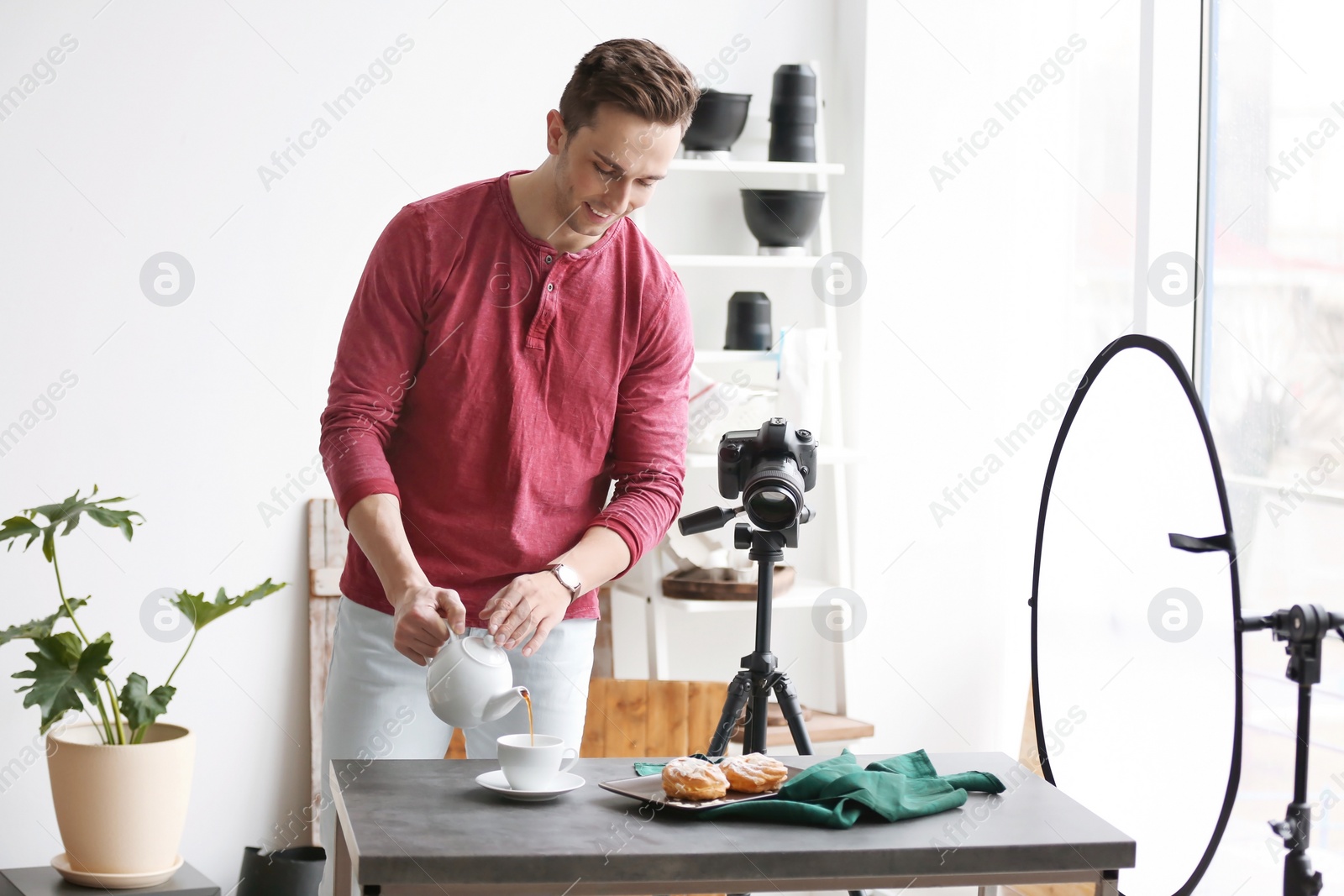 Photo of Young man with professional camera preparing food composition in photo studio