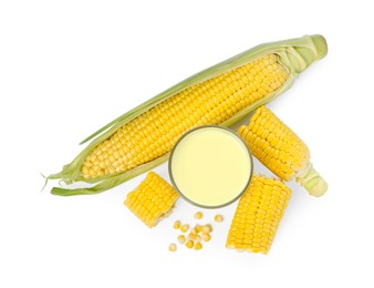 Photo of Tasty fresh corn milk in glass and cobs on white background, top view