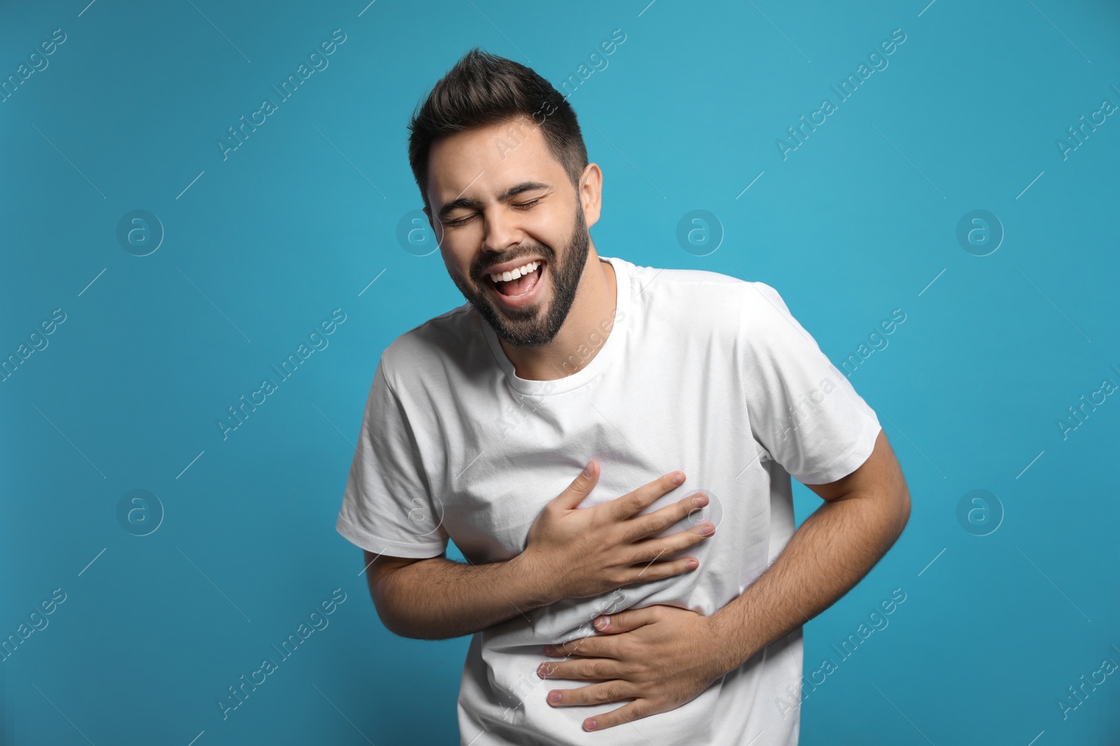 Photo of Young man laughing on light blue background. Funny joke