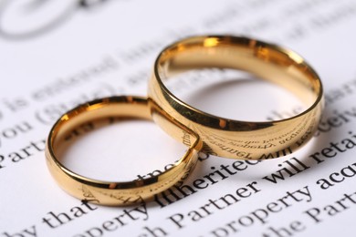Photo of Marriage contract and gold rings on table, closeup