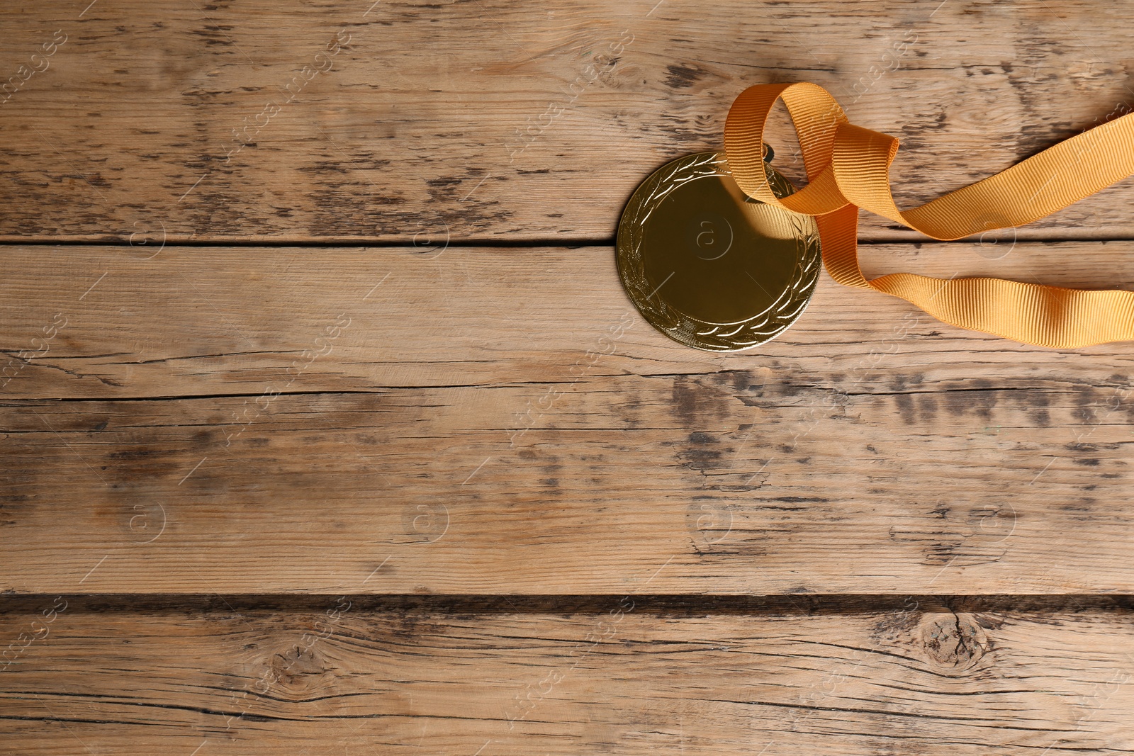 Photo of Medal with yellow ribbon on wooden background, closeup. Space for design