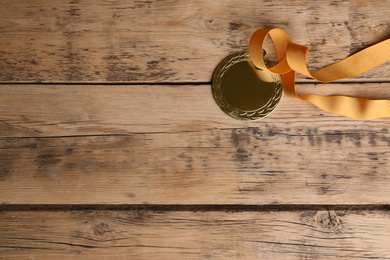 Medal with yellow ribbon on wooden background, closeup. Space for design