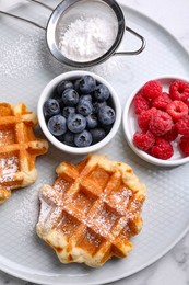 Photo of Delicious Belgian waffles with fresh berries and powdered sugar on table, top view