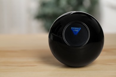 Photo of Magic eight ball with prediction Prospect Good on wooden table, closeup. Space for text