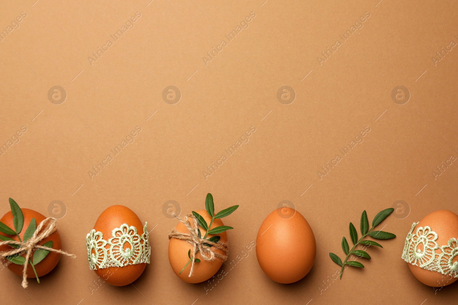 Photo of Festively decorated chicken eggs on brown background, flat lay and space for text. Happy Easter