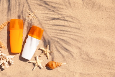 Photo of Flat lay composition with bottles of sunblock on sandy beach. Space for text