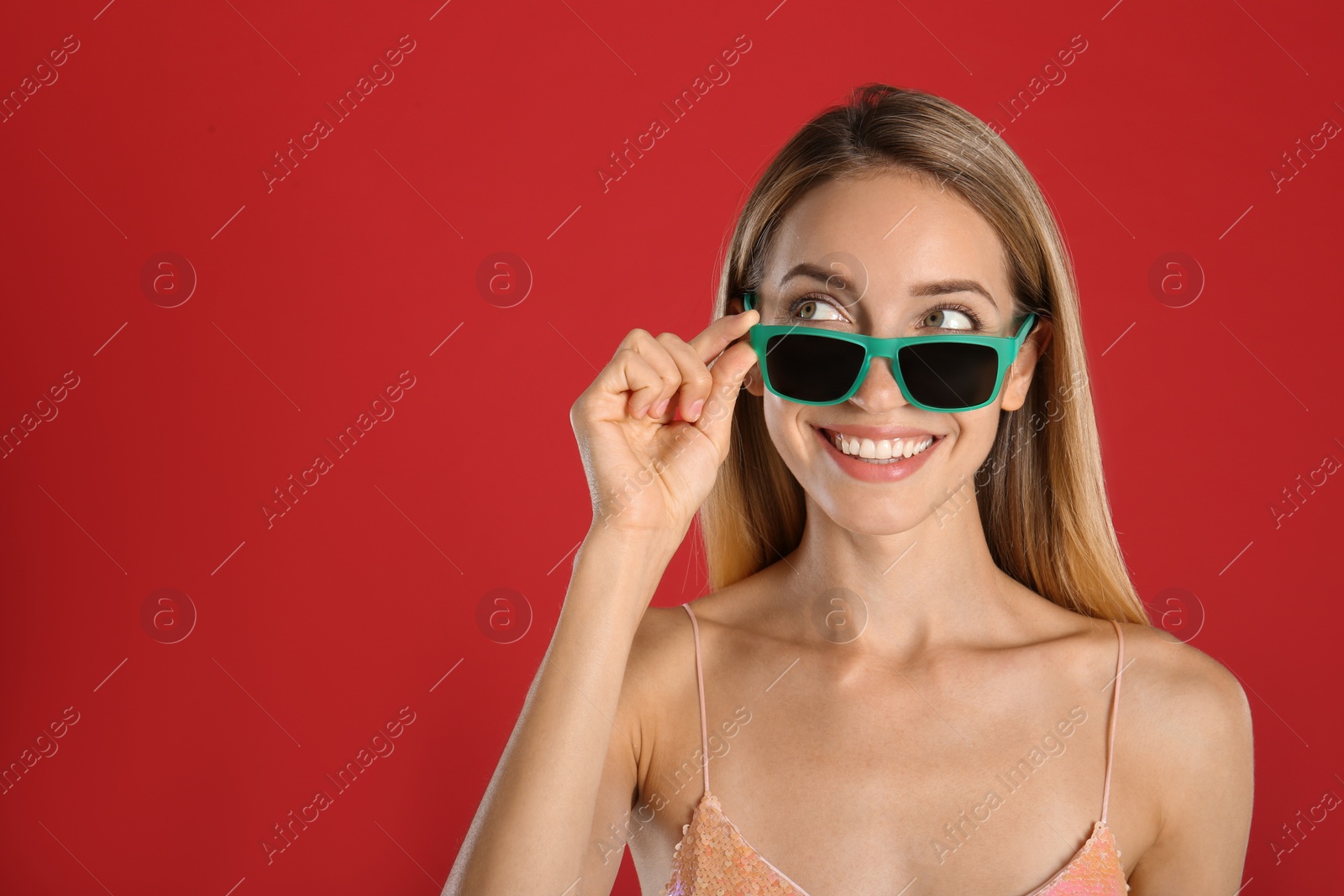 Photo of Beautiful woman in stylish sunglasses on red background. Space for text