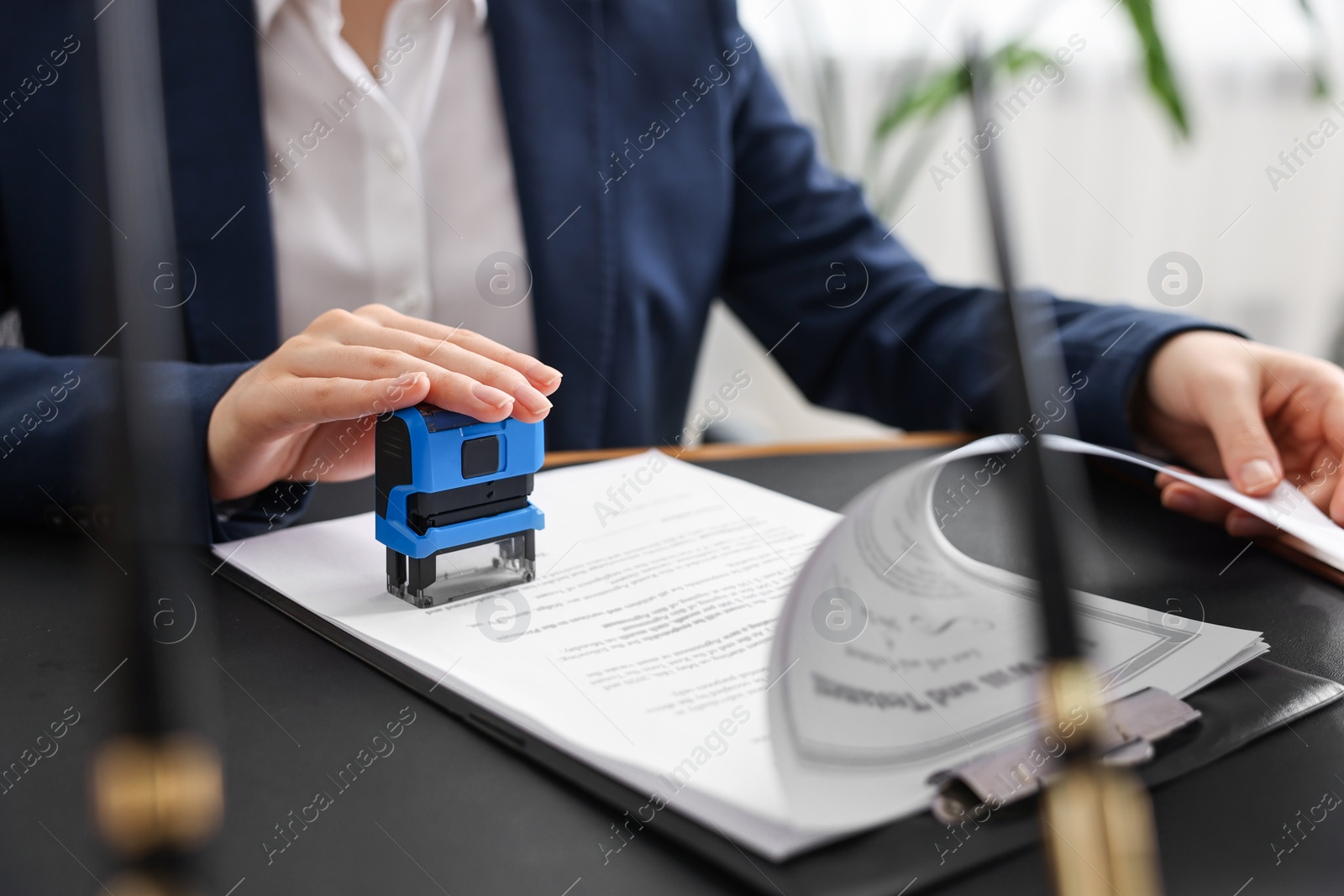 Photo of Notary stamping document at table in office, closeup