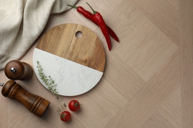 Photo of Cutting board and different spices on wooden table, flat lay. Space for text