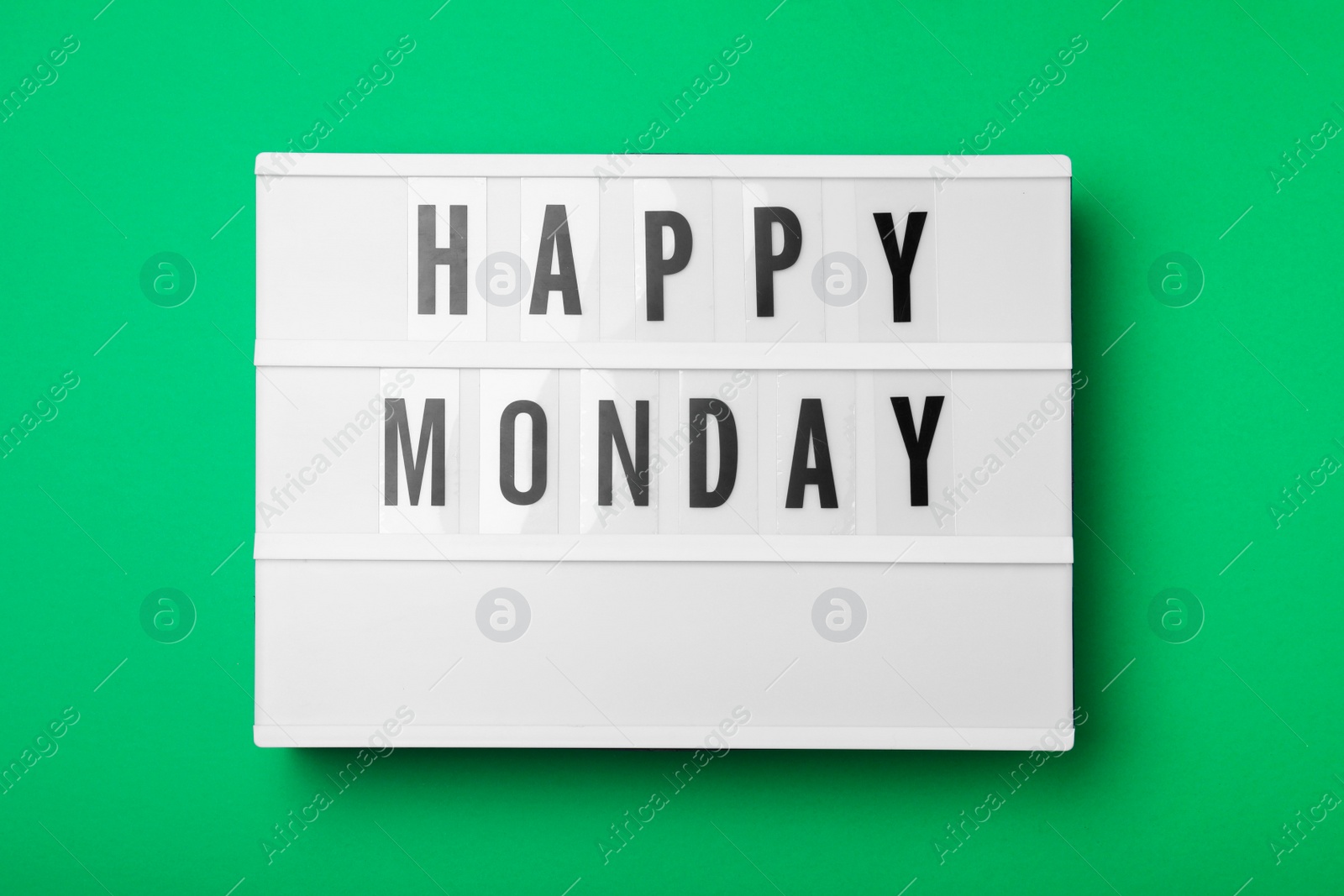 Photo of Light box with message Happy Monday on green background, top view