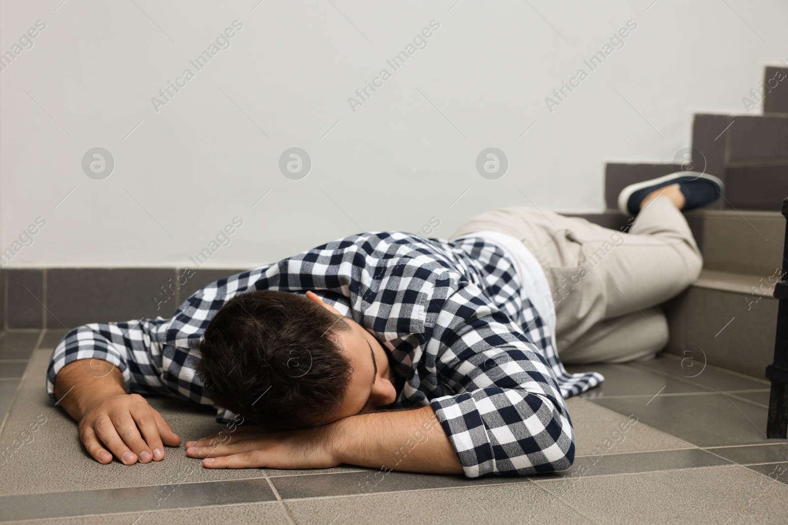 Photo of Unconscious man lying on floor after falling down stairs indoors