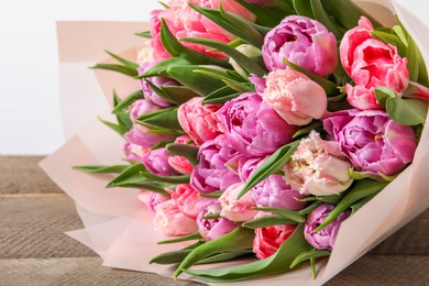 Photo of Bouquet of beautiful tulips on wooden table, closeup