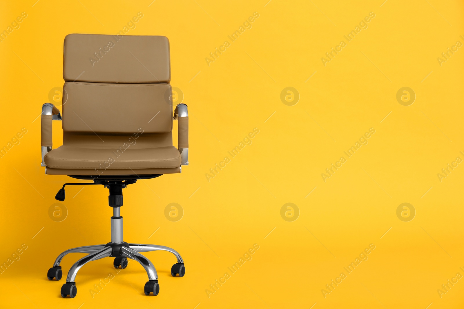 Photo of Modern office chair on yellow background. Space for text