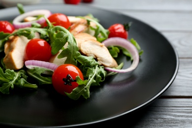 Photo of Delicious salad with chicken, vegetables and arugula  on grey table, closeup