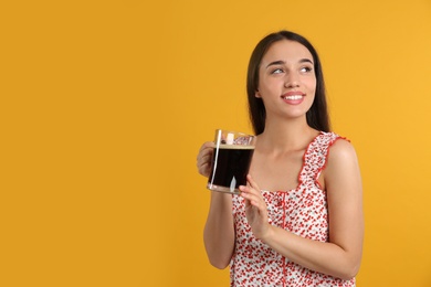 Photo of Beautiful woman with cold kvass on yellow background. Traditional Russian summer drink