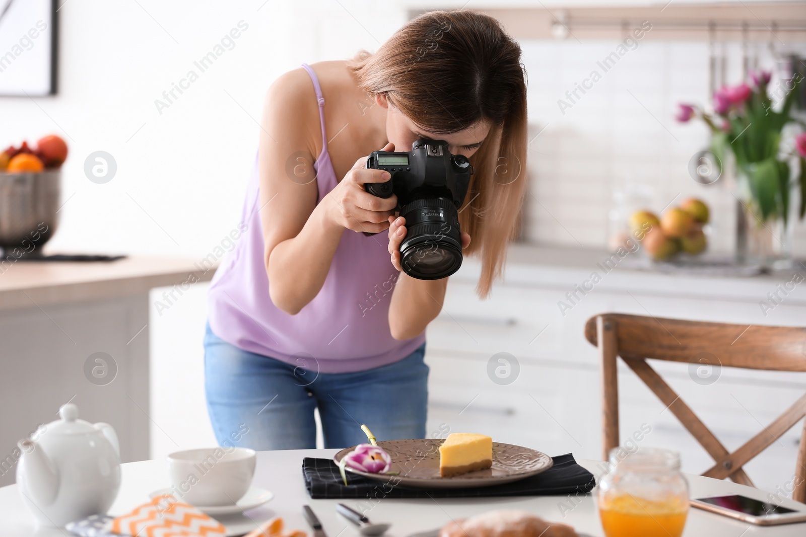 Photo of Young blogger taking photo of food in kitchen