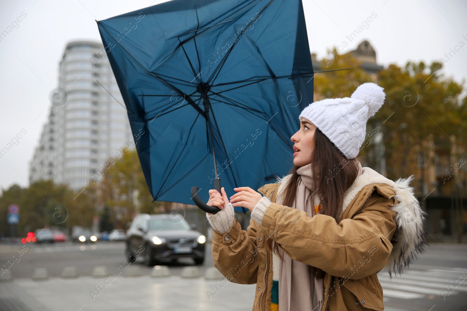 Photo of Woman with blue umbrella caught in gust of wind on street