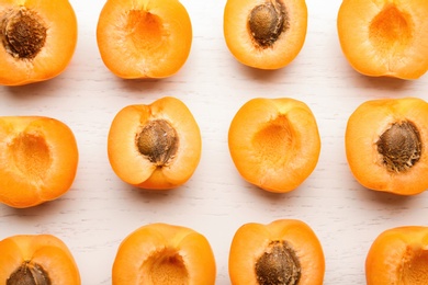 Flat lay composition with delicious ripe apricots on white wooden background