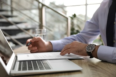 Photo of Businessman working with documents at wooden desk in office, closeup