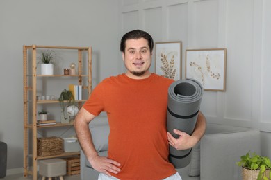 Photo of Overweight man with yoga mat at home