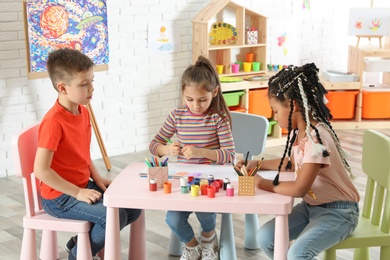 Cute little children drawing at painting lesson indoors