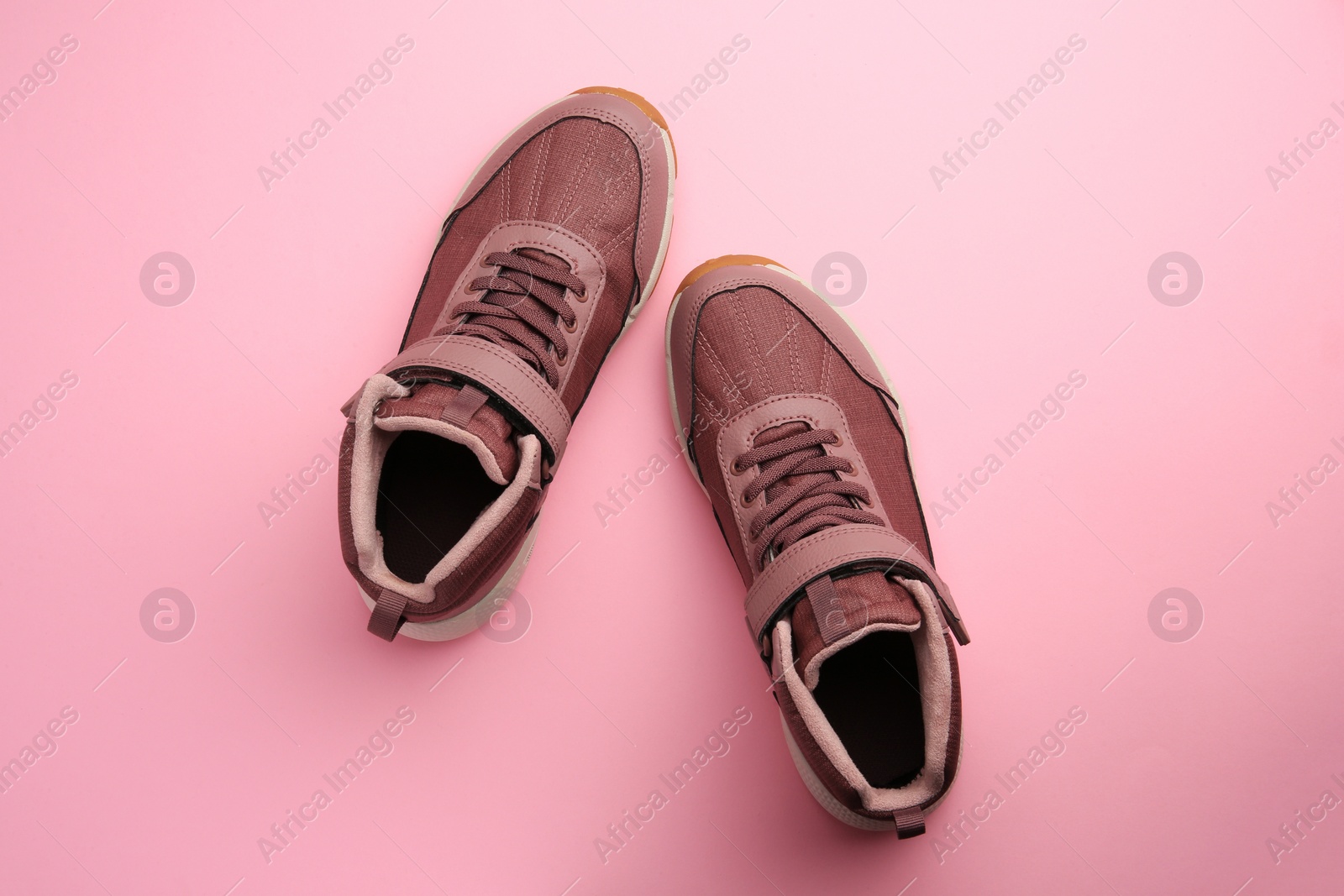 Photo of Pair of stylish kid's sneakers on pink background, top view