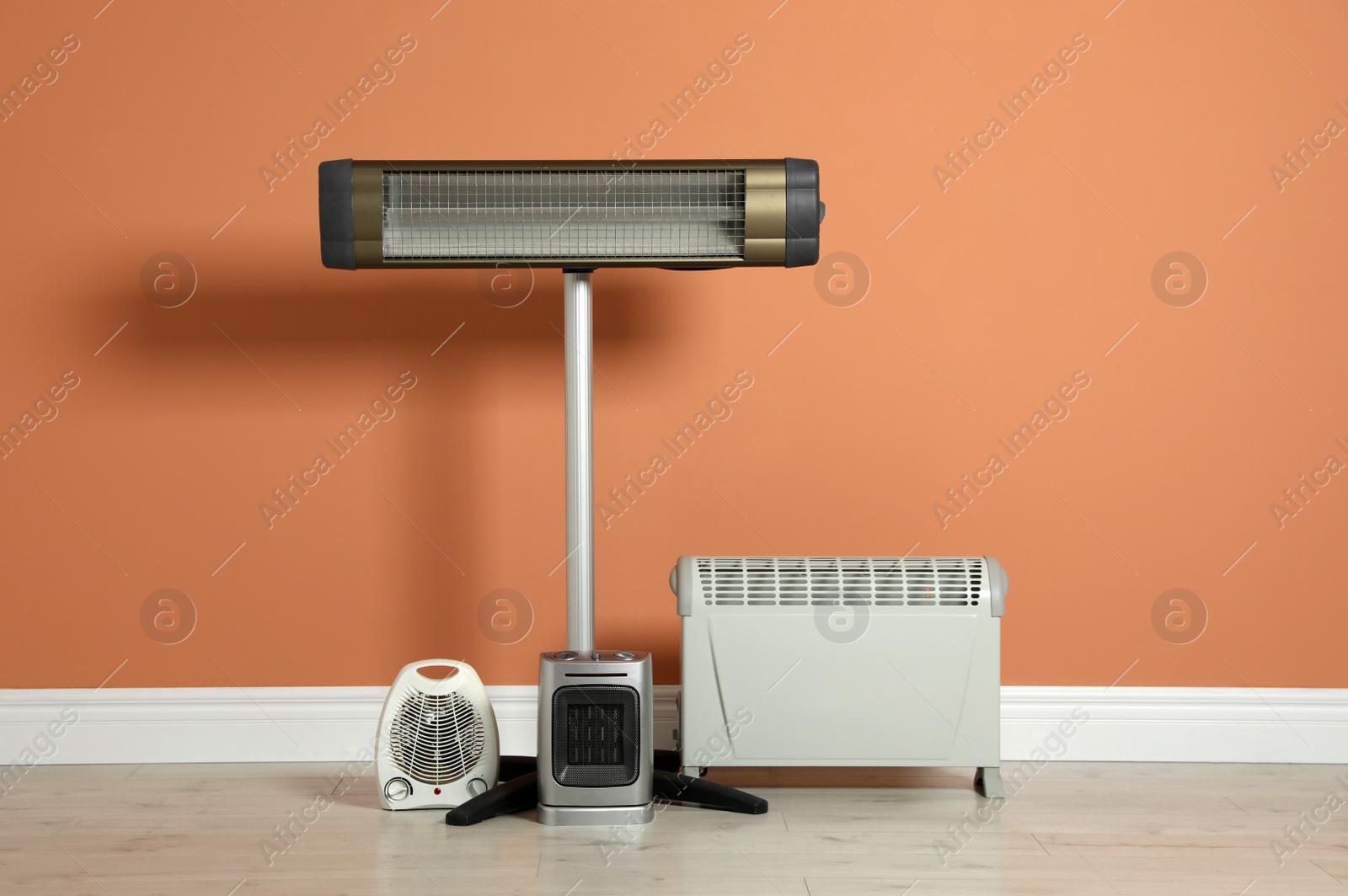 Photo of Different electric heaters near orange wall indoors