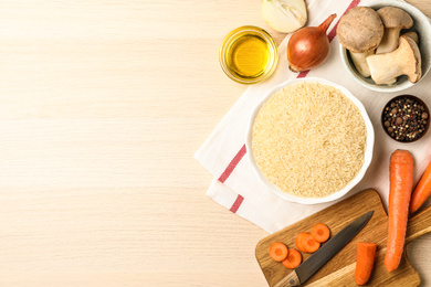 Photo of Flat lay composition with different ingredients on wooden table, space for text. Risotto recipe