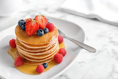 Tasty pancakes with berries and honey on plate