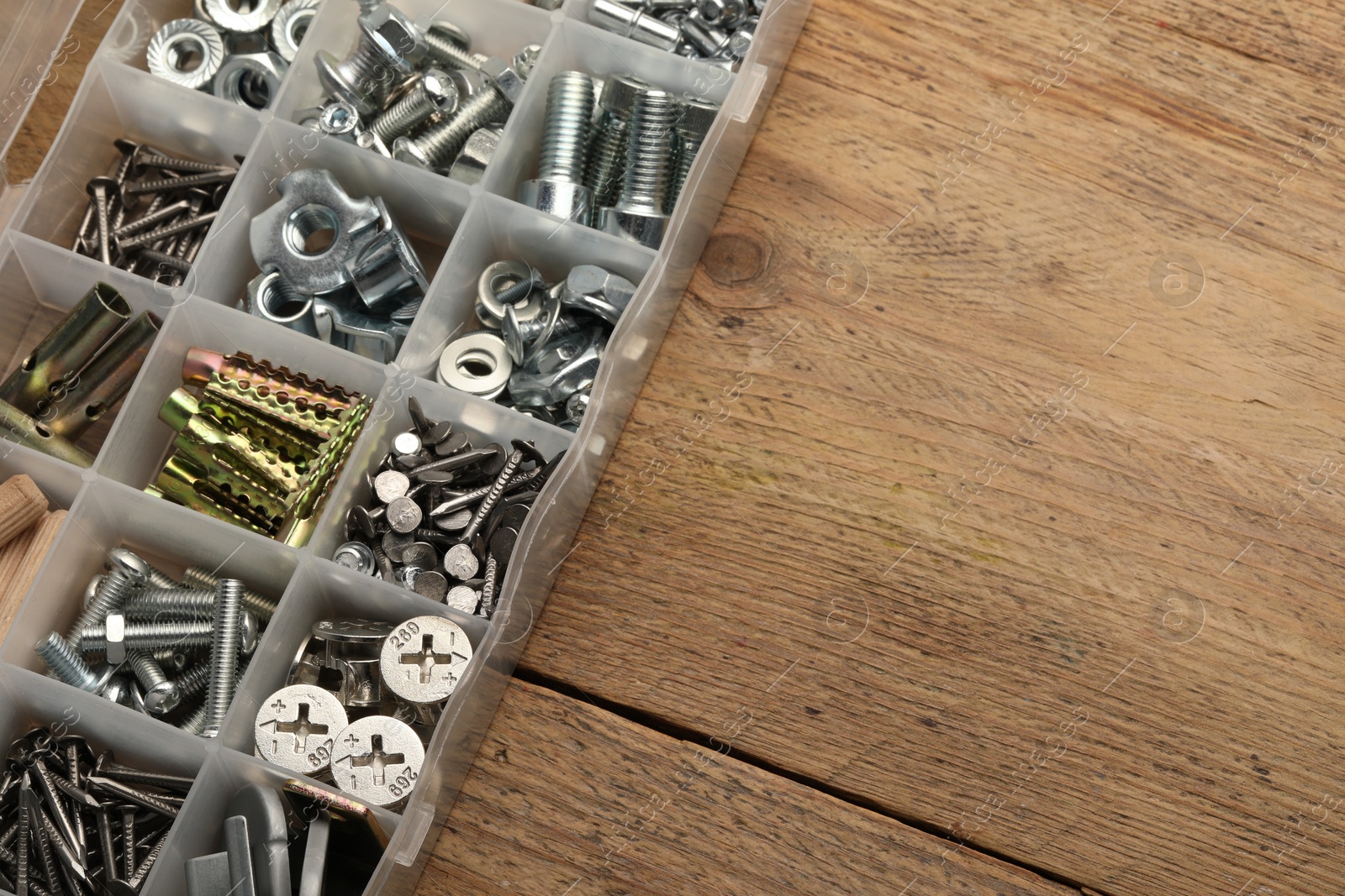 Photo of Organizer with many different fasteners on wooden table, above view. Space for text