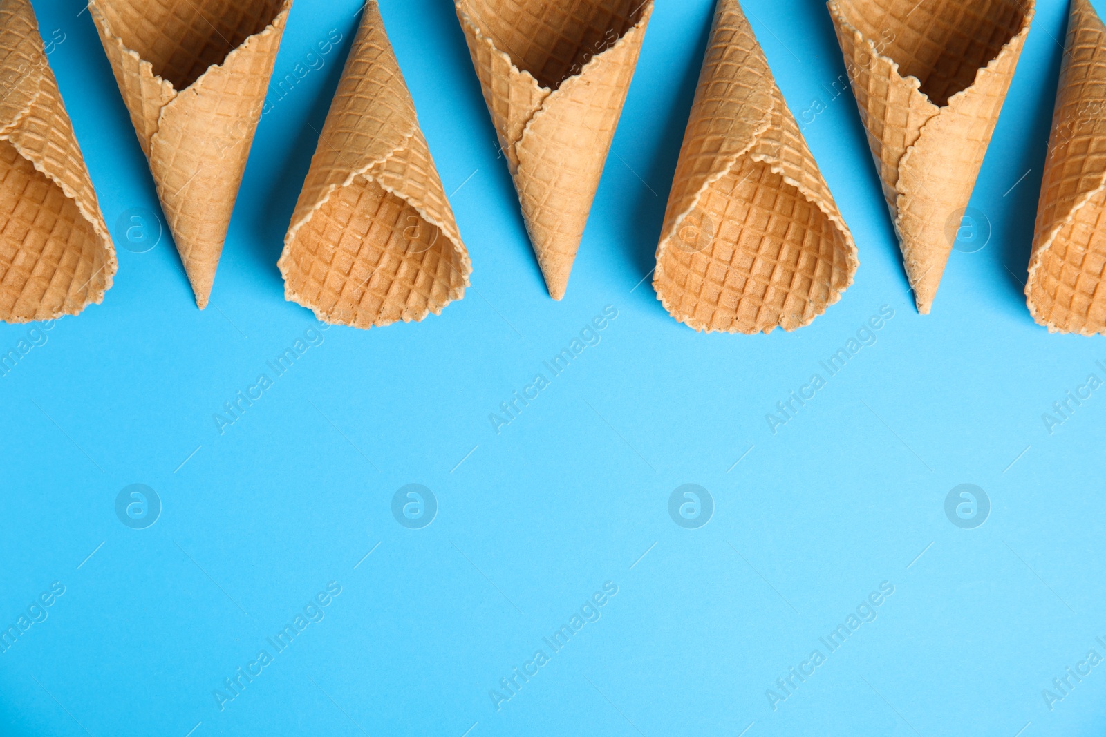 Photo of Waffle empty ice cream cones on color background, flat lay. Space for text
