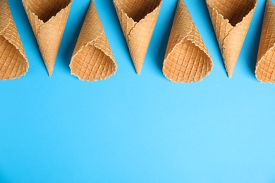 Waffle empty ice cream cones on color background, flat lay. Space for text