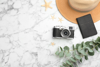 Flat lay composition with professional photographer camera, passport and space for text on white marble table