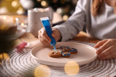 Little child decorating Christmas cookie at table, closeup