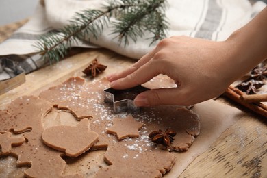 Photo of Woman making gingerbread Christmas cookies at wooden table, closeup