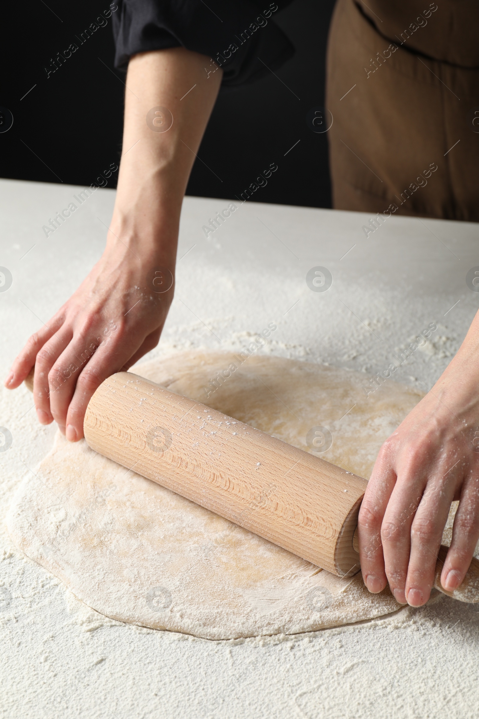 Photo of Woman rolling raw dough at table, closeup