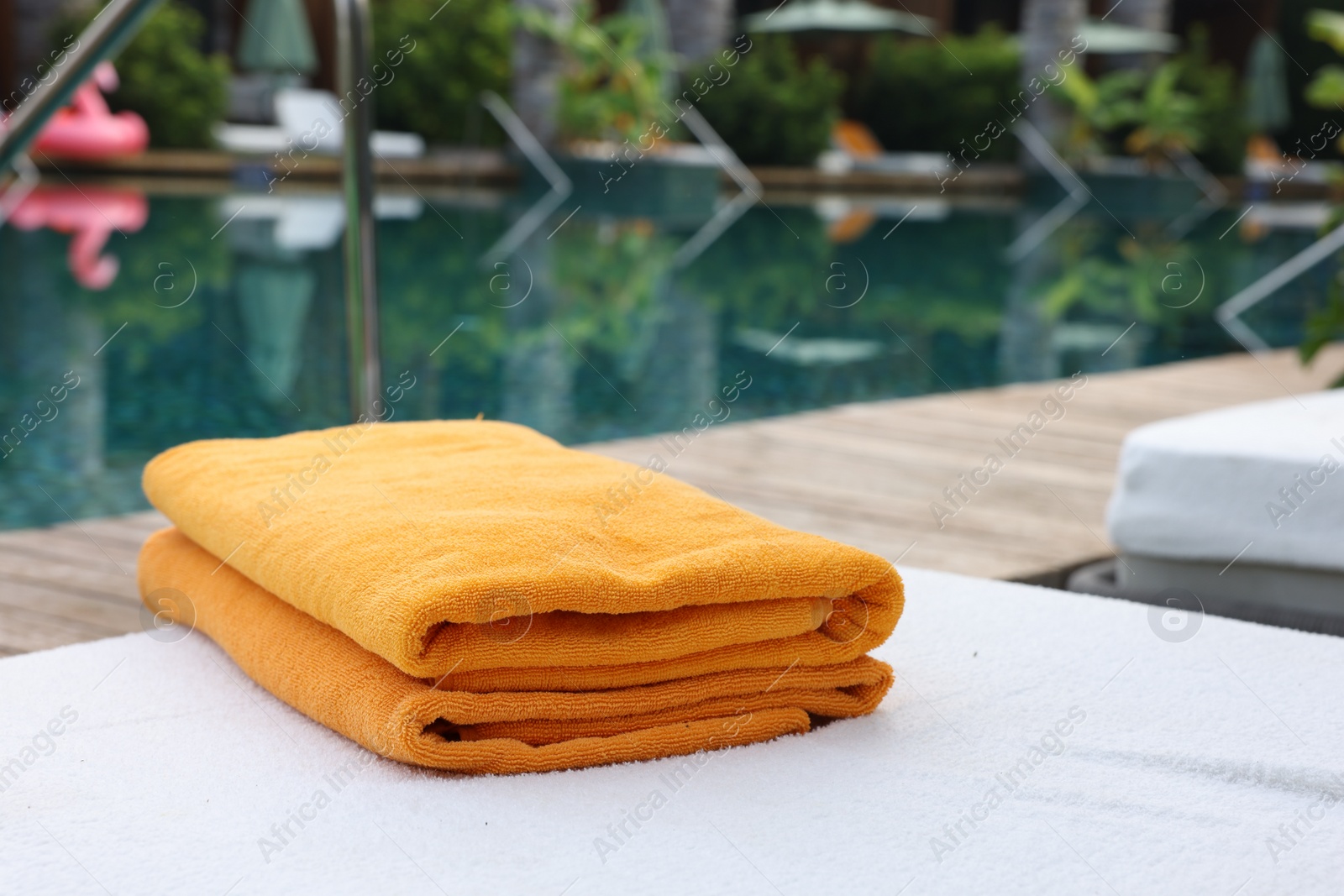 Photo of Beach towels on sun lounger near outdoor swimming pool, space for text. Luxury resort