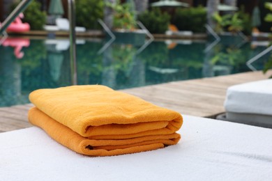 Beach towels on sun lounger near outdoor swimming pool, space for text. Luxury resort