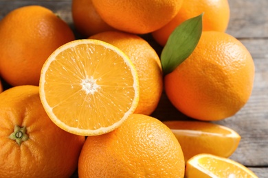 Fresh oranges with leaves on wooden table, closeup