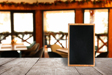 Blank small blackboard on wooden table in cafe, mockup for menu design 