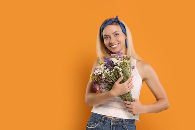 Happy hippie woman with bouquet of flowers on orange background. Space for text