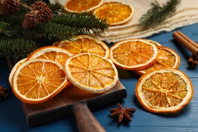 Photo of Dry orange slices, cinnamon and anise stars on blue wooden table, closeup
