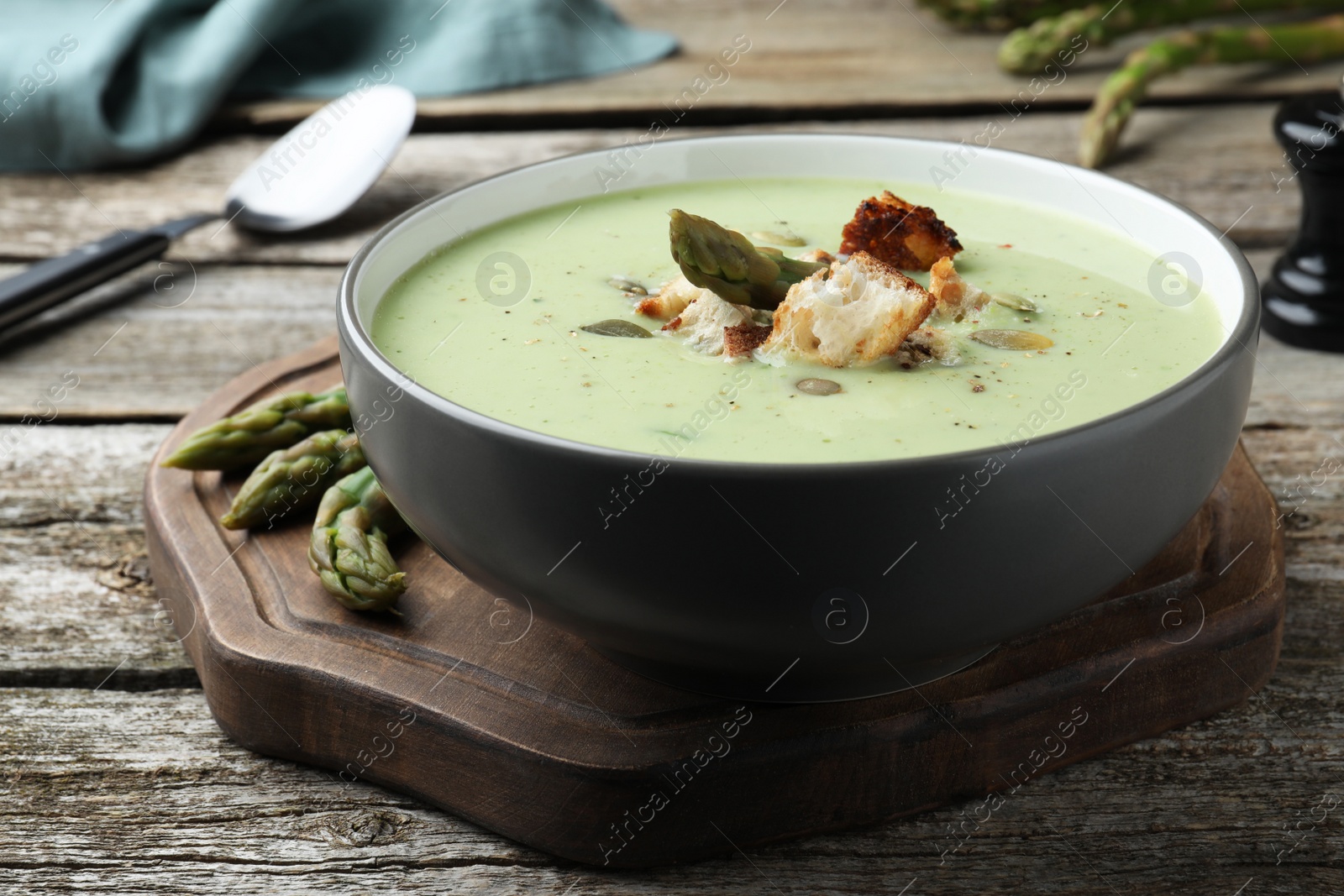 Photo of Bowl of delicious asparagus soup on wooden table