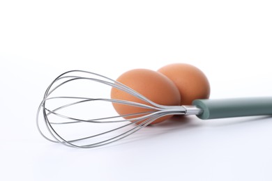 Photo of Whisk and raw eggs isolated on white