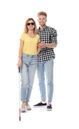 Young man helping blind person with long cane on white background